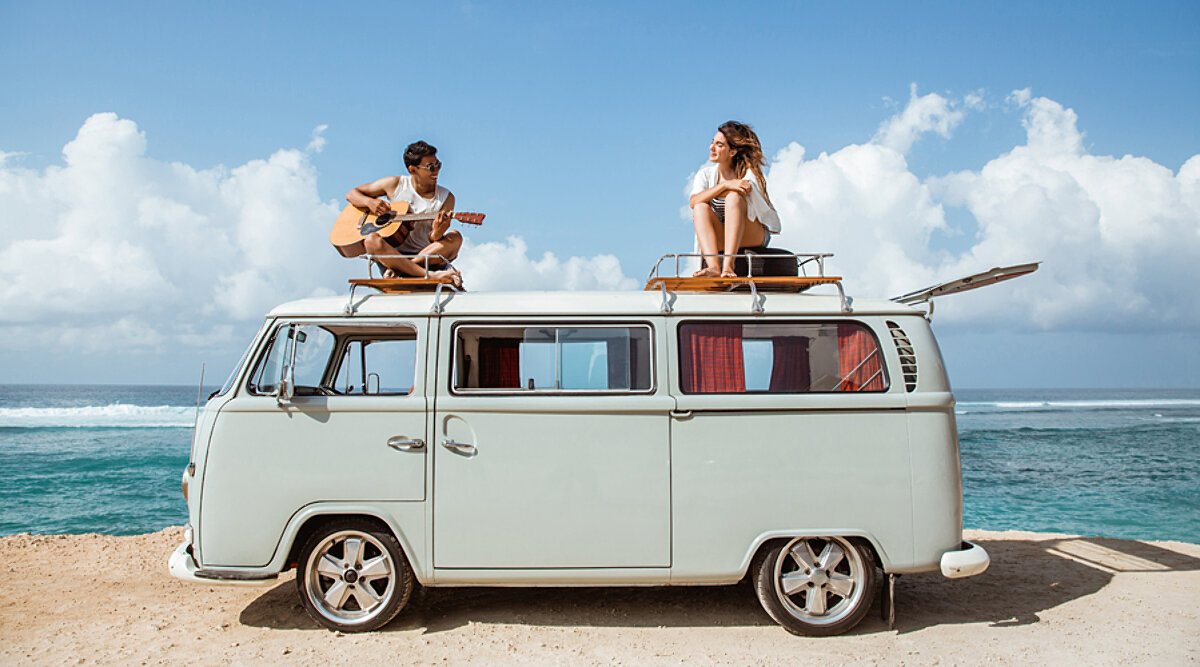 Two people sitting on a campervan rooftop playing music