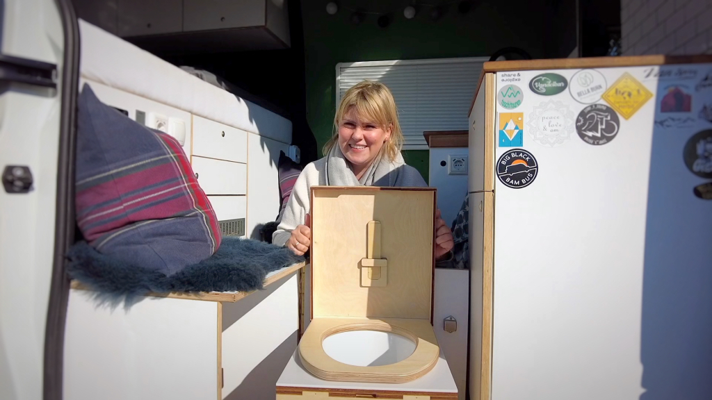 Eine Frau sitzt in ihrem Campervan und präsentiert ihre Kildwick Toilette.